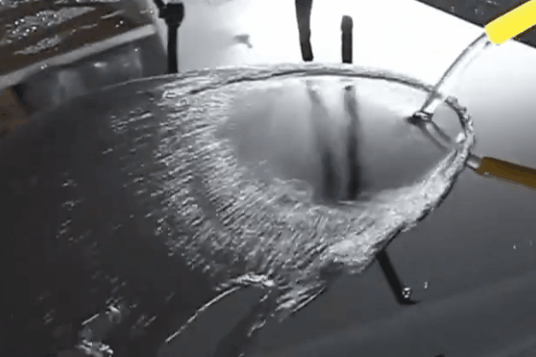 Water beading and sheeting across a ceramic-coated vehicle surface to demonstrate hydrophobic behavior.